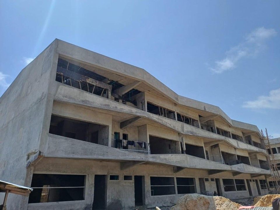 Edificio: a three-storey concrete carcass with deep balconies and a sloped parapet