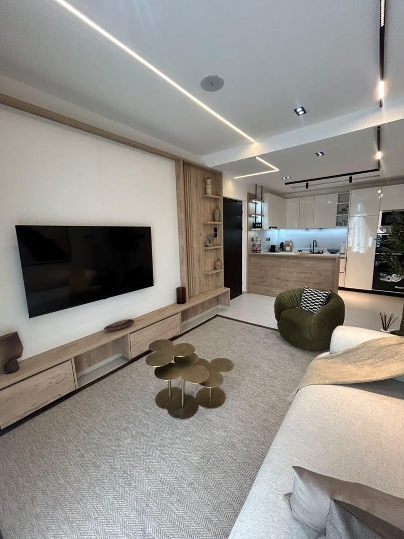 Norden living room: timber media wall with display shelving, linear ceiling lights and the kitchen beyond