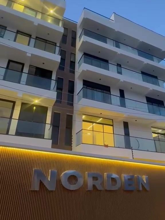 Norden Apartments: two white blocks with glass balconies above a timber-clad boundary wall